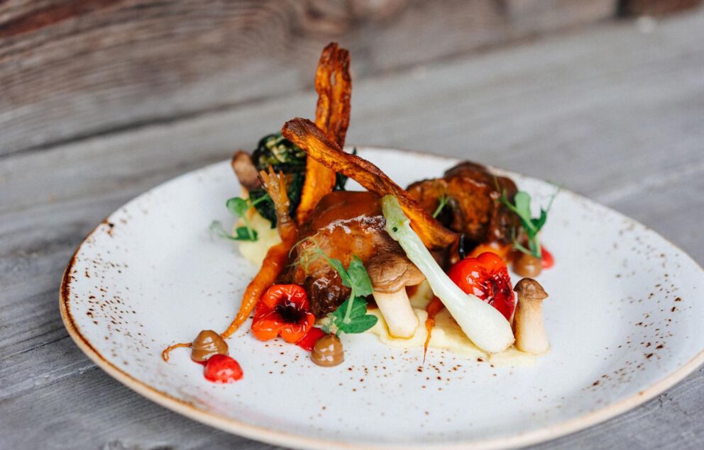 Piatto di carne con patate dolci fritte, funghi e altre verdure su un piatto.